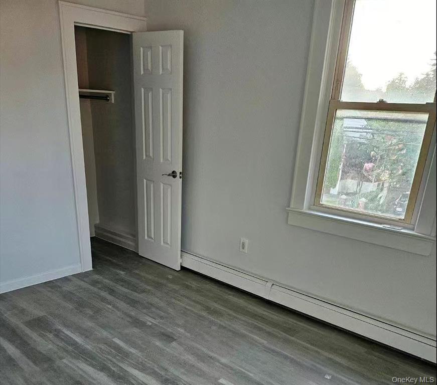 144-18 Negundo Avenue Queens, NY 11355 - Photo 6 of 7 an empty room with wooden floor and a window
