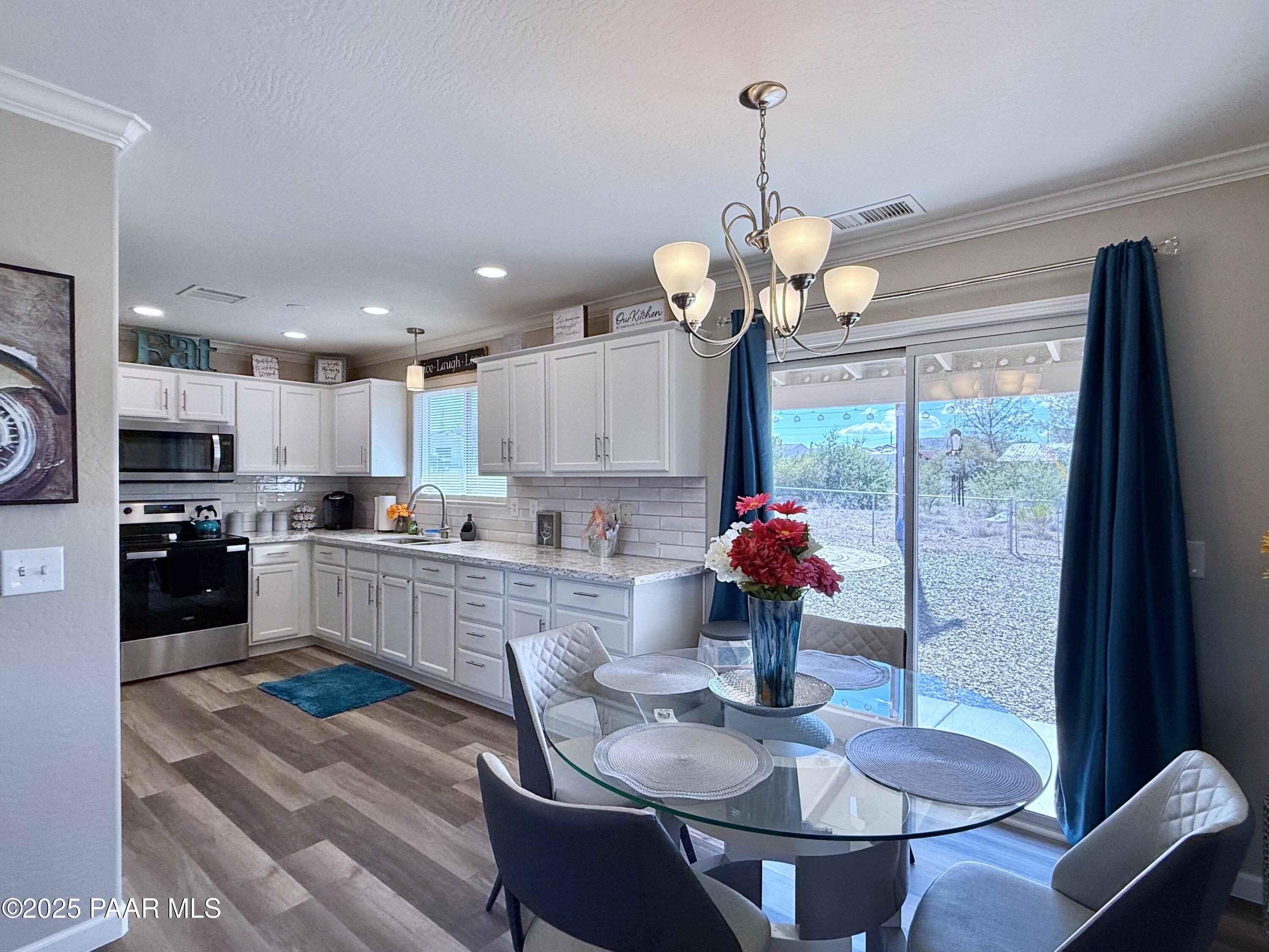 20233 East Sunset Lane Mayer, AZ 86333 - Photo 14 of 42 a kitchen with stainless steel appliances granite countertop a stove refrigerator a dining table and chairs with wooden floor