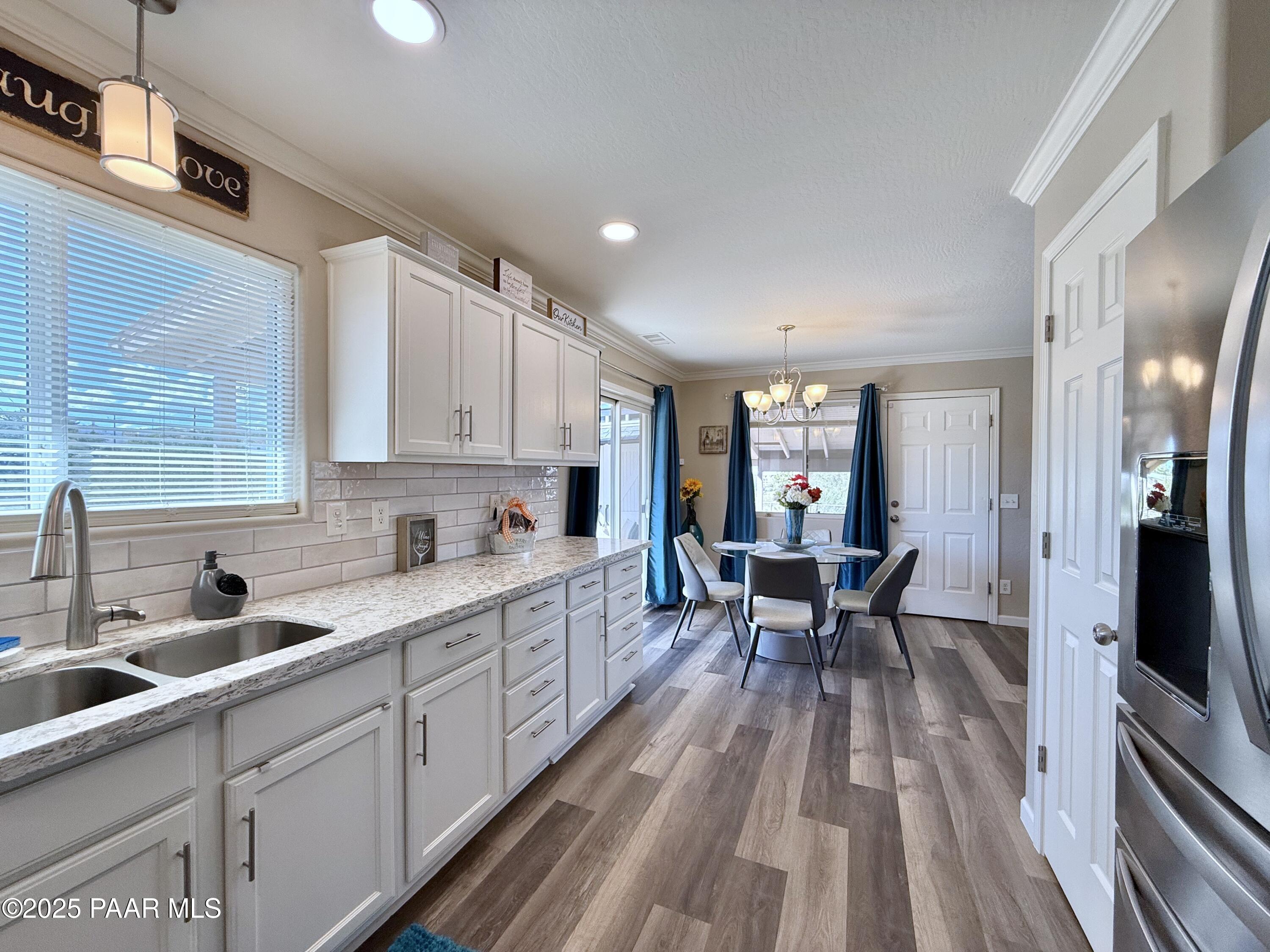 20233 East Sunset Lane Mayer, AZ 86333 - Photo 20 of 42 a kitchen with white cabinets sink dining table and chairs