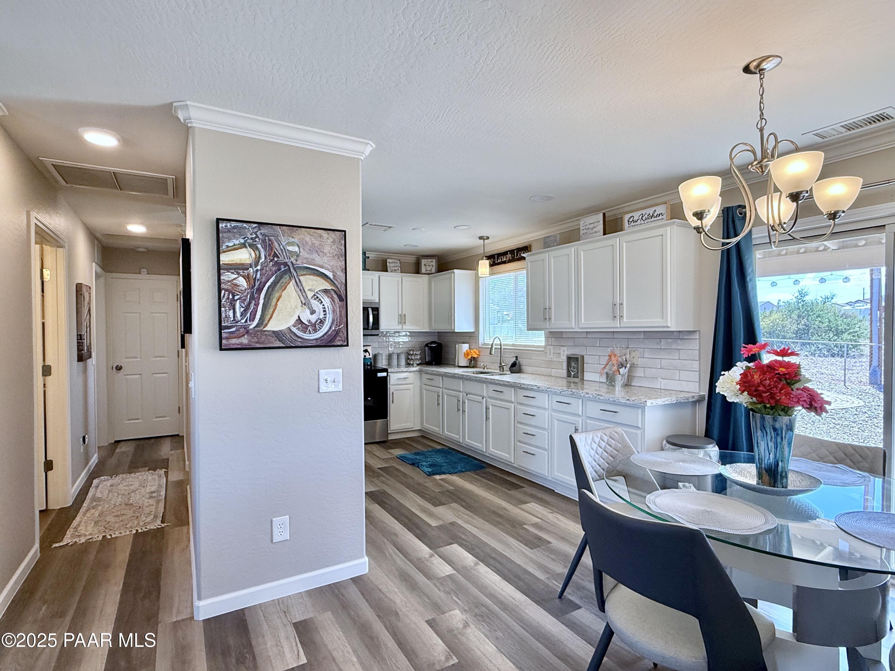 20233 East Sunset Lane Mayer, AZ 86333 - Photo 24 of 42 a kitchen with stainless steel appliances granite countertop a refrigerator a sink dishwasher a dining table and chairs with wooden floor