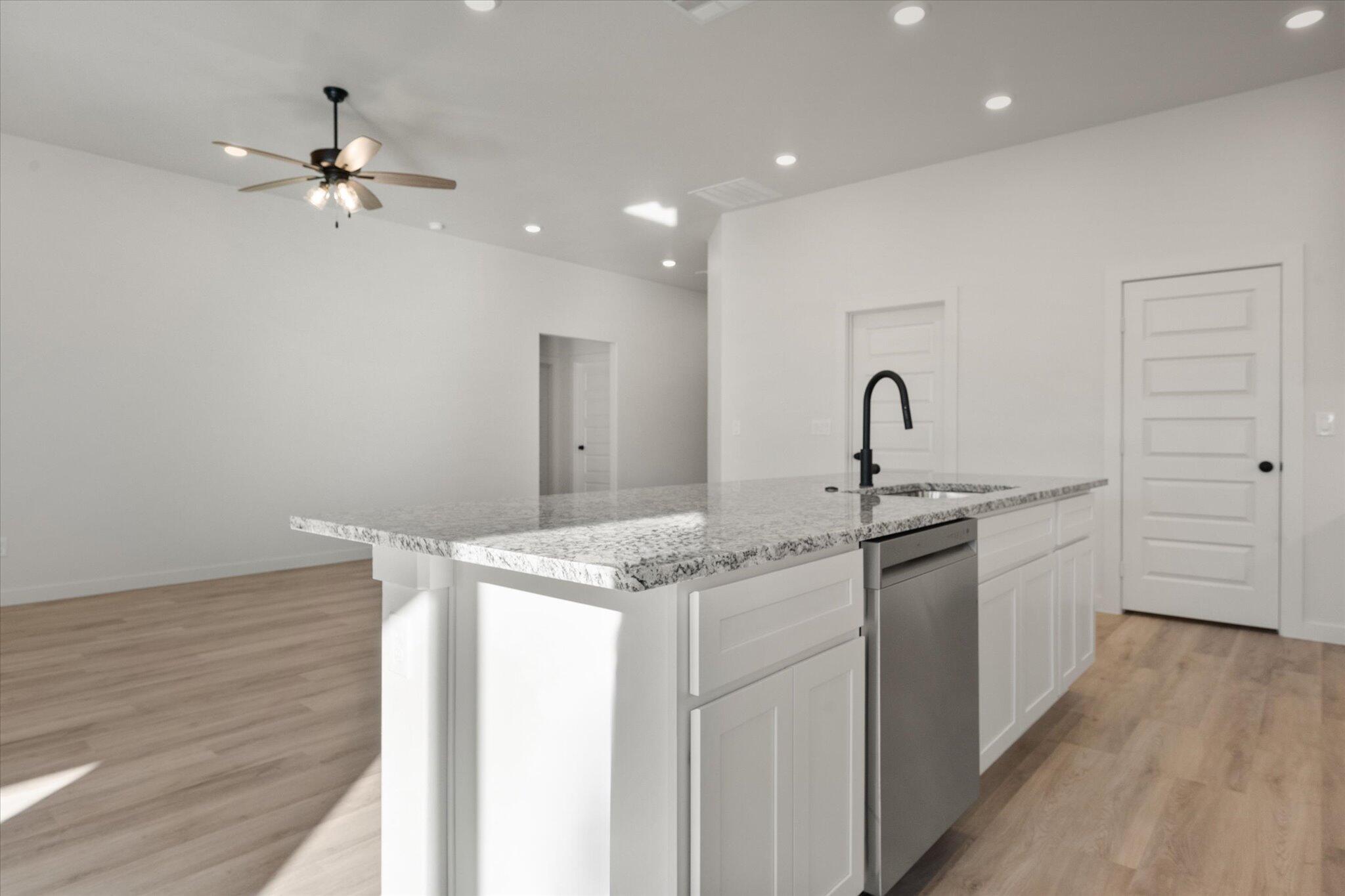 709 East 30th Street Wolfforth, TX 79382 - Photo 11 of 25 a kitchen with granite countertop a sink cabinets and wooden floor