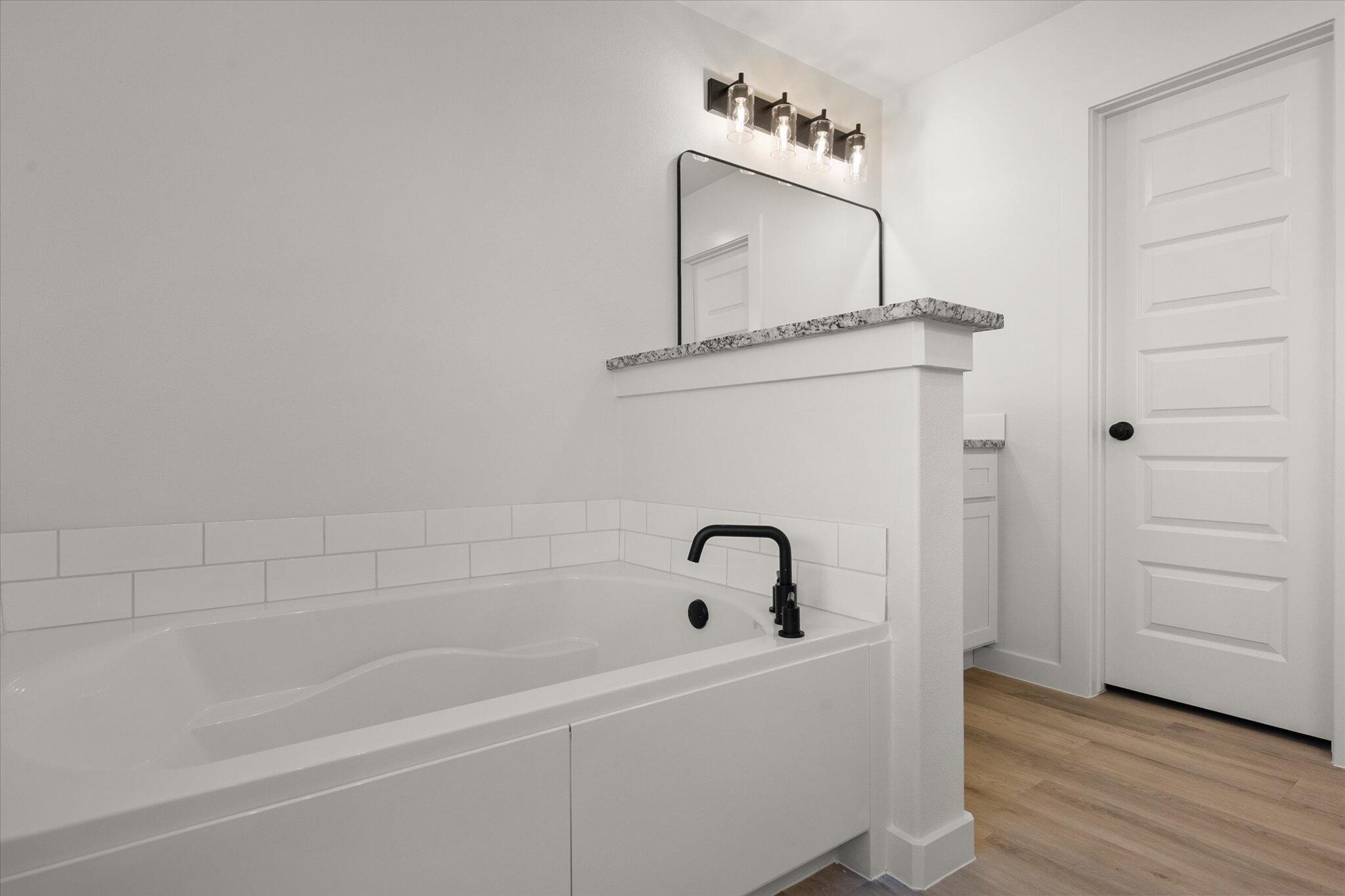 709 East 30th Street Wolfforth, TX 79382 - Photo 17 of 25 a bathroom with a bathtub and a mirror
