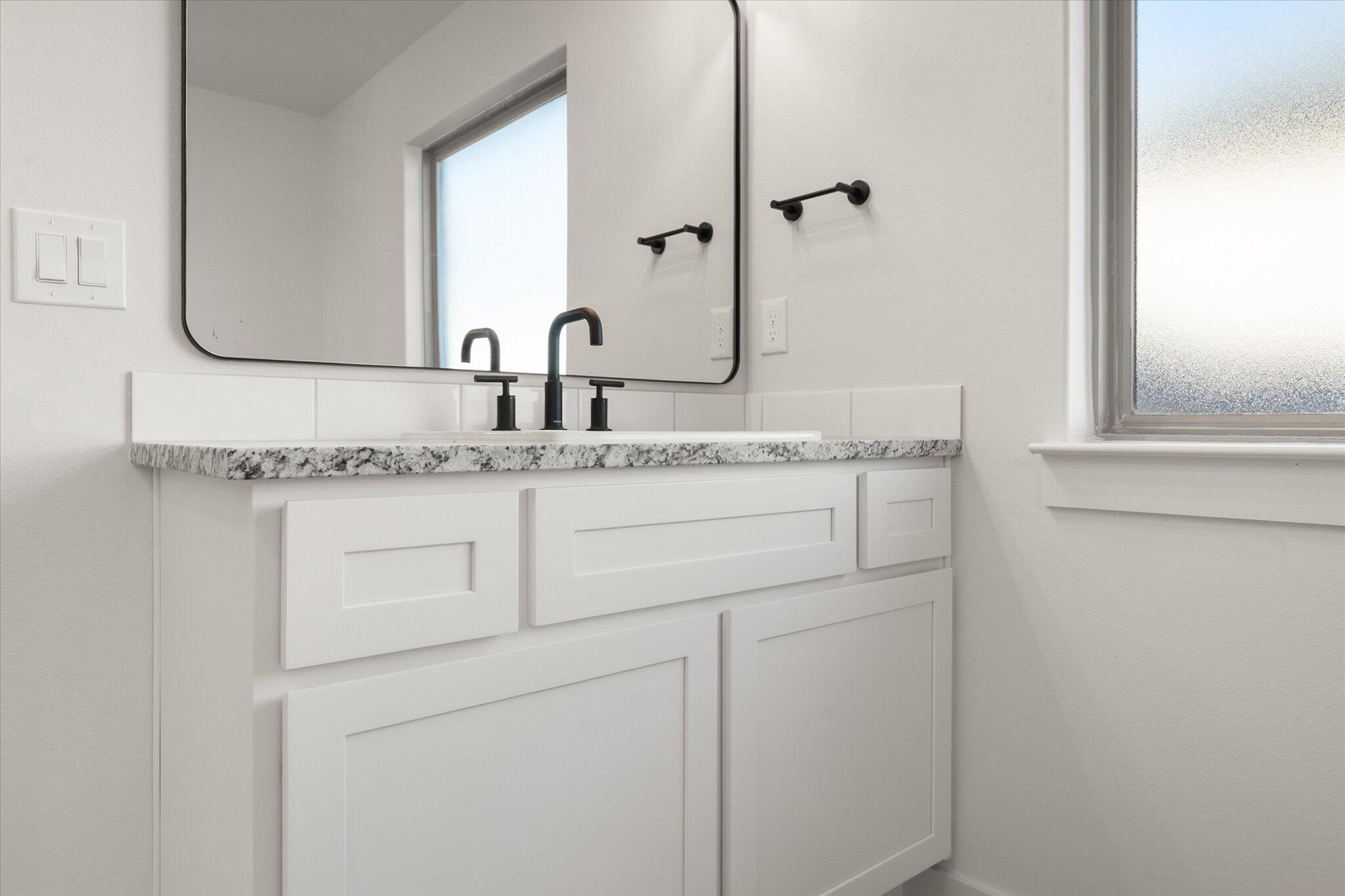 709 East 30th Street Wolfforth, TX 79382 - Photo 18 of 25 a bathroom with a granite countertop sink and a mirror