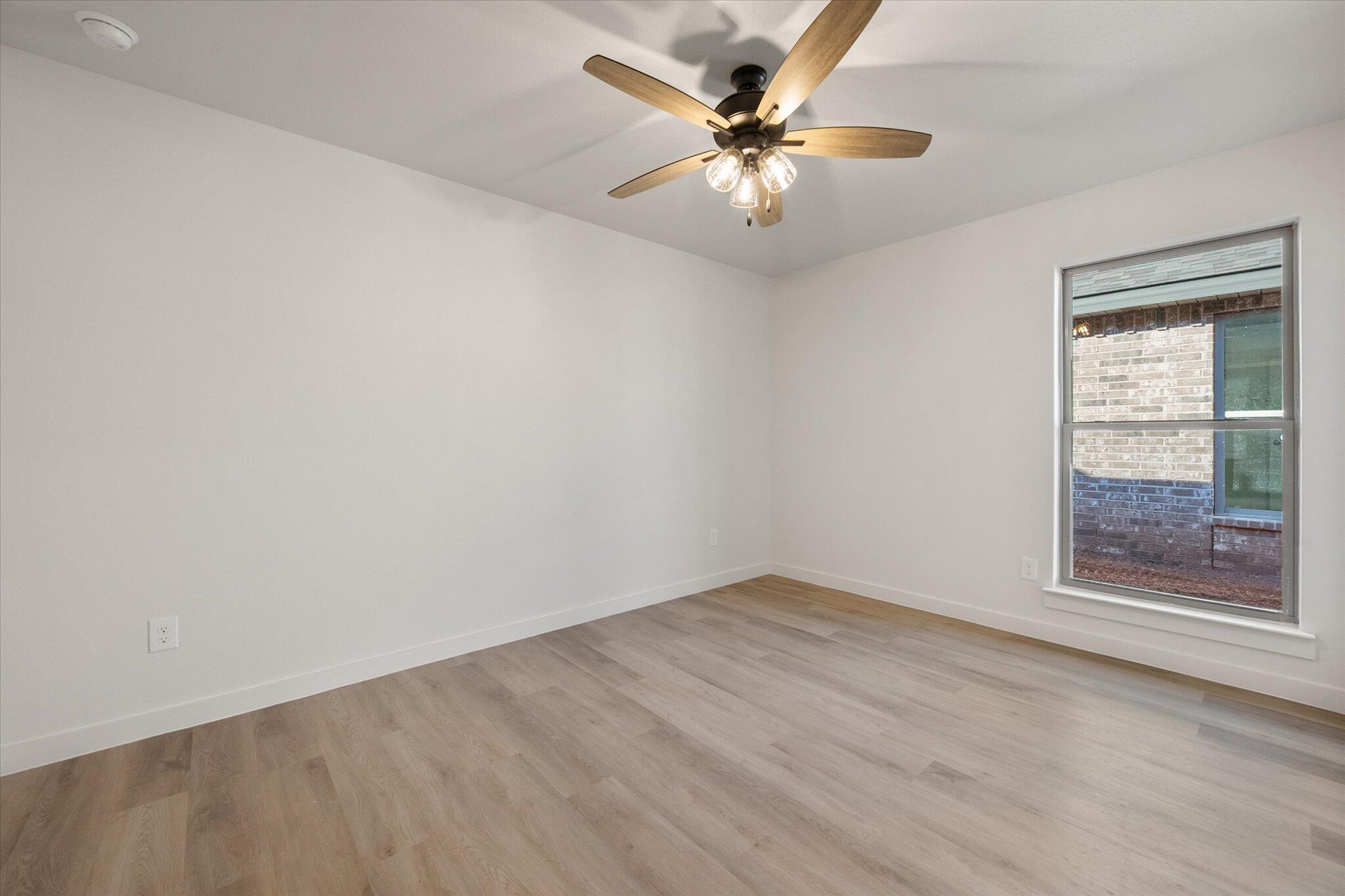 709 East 30th Street Wolfforth, TX 79382 - Photo 22 of 25 an empty room with a chandelier fan and windows