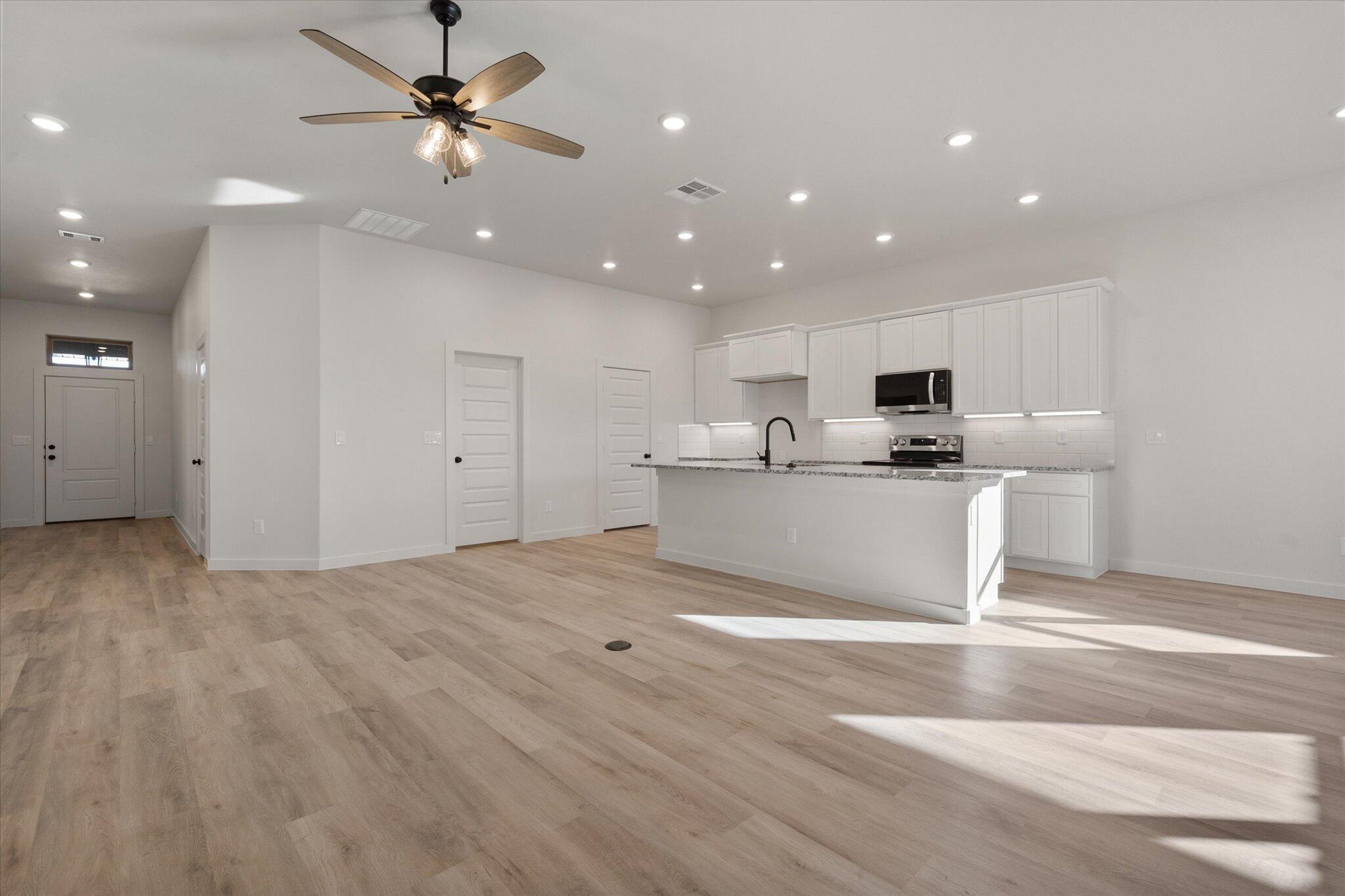 709 East 30th Street Wolfforth, TX 79382 - Photo 6 of 25 a view of a kitchen with stainless steel appliances granite countertop a stove a sink a refrigerator white cabinets and wooden floor
