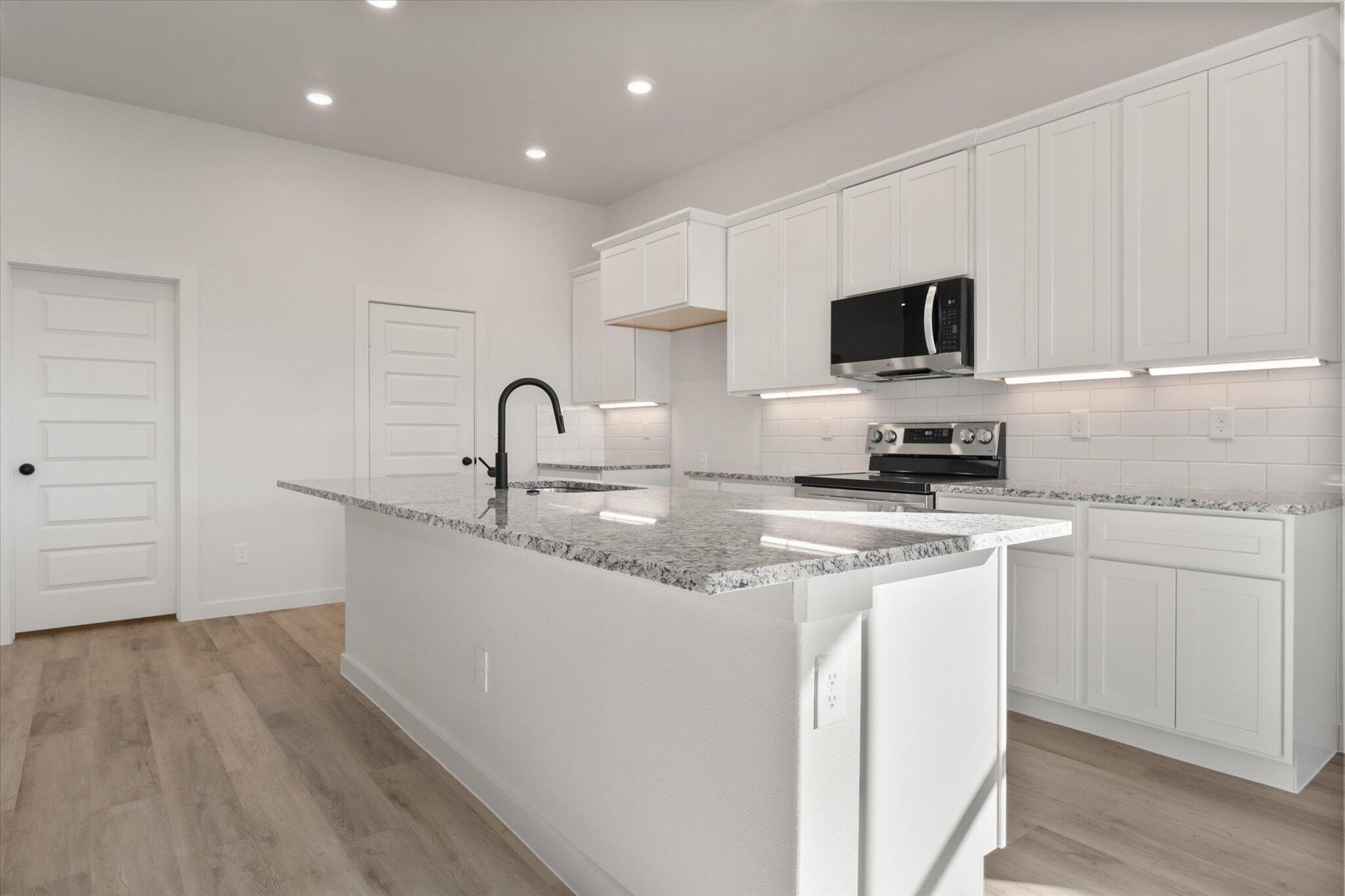 709 East 30th Street Wolfforth, TX 79382 - Photo 7 of 25 a kitchen with stainless steel appliances granite countertop a sink a stove and microwave with wooden floor