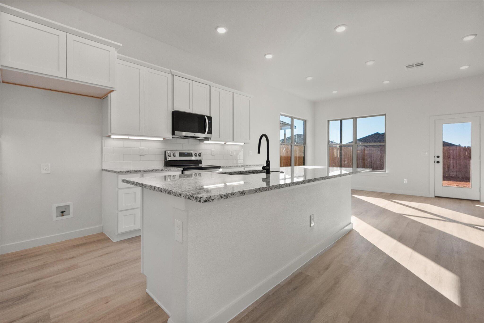 709 East 30th Street Wolfforth, TX 79382 - Photo 9 of 25 a kitchen with granite countertop a sink and a stove top oven