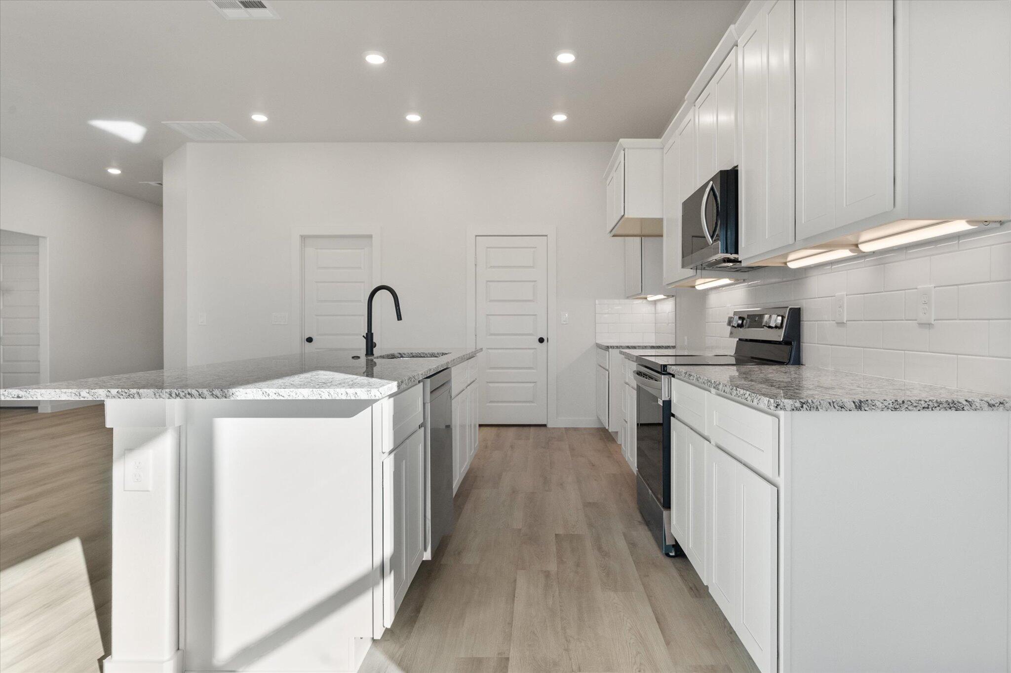 709 East 30th Street Wolfforth, TX 79382 - Photo 10 of 25 a kitchen with kitchen island granite countertop a sink and wooden cabinets