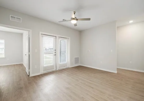 a view of an empty room with wooden floor and a window