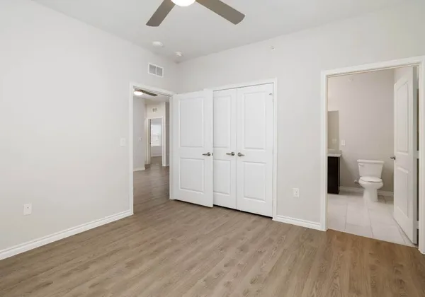 an empty room with wooden floor and a ceiling fan