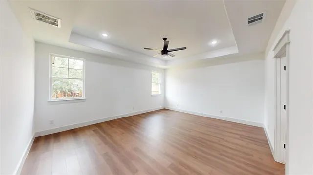 an empty room with wooden floor and windows