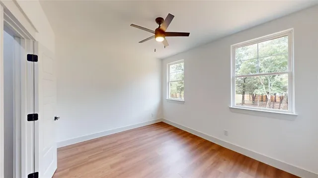 a view of empty room with wooden floor and fan