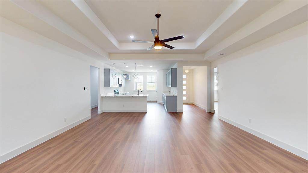 416 Linden Street Keene, TX 76059 - Photo 4 of 33 a view of an empty room with wooden floor and a kitchen