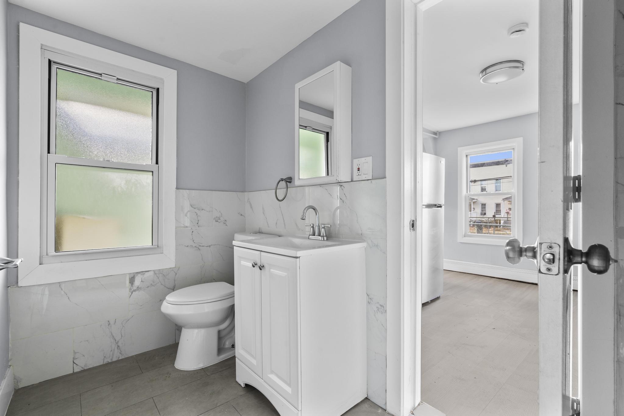 746 Maple Street Bridgeport, CT 06608 - Photo 18 of 38 a spacious bathroom with a toilet sink and a mirror