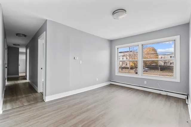 a view of an empty room with a window and wooden floor