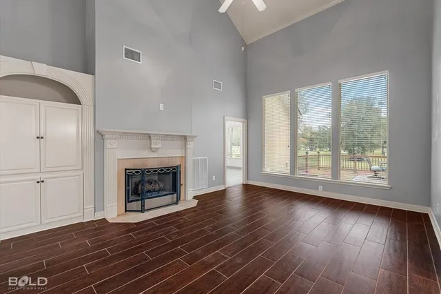 an empty room with wooden floor fireplace and windows