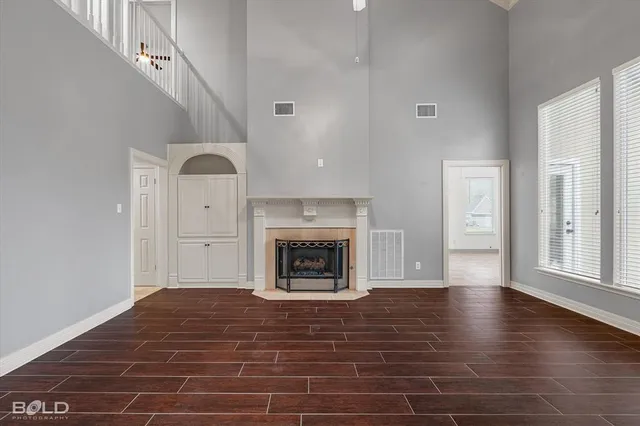 a view of an empty room with wooden floor fireplace and a window