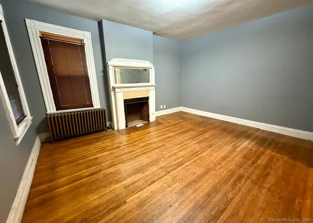 a view of empty room with fireplace and wooden floor