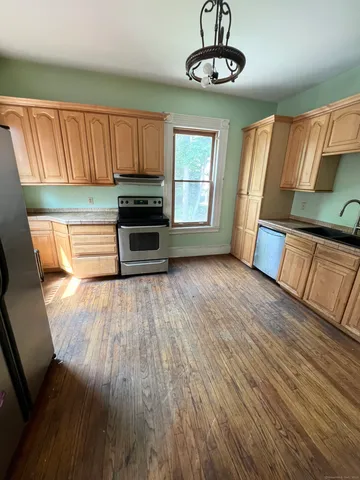 a kitchen with stainless steel appliances granite countertop a stove top oven a refrigerator with wooden floors and cabinets