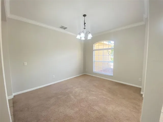 an empty room with chandelier and windows
