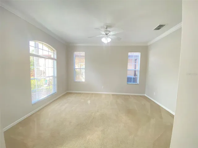 an empty room with windows and chandelier fan