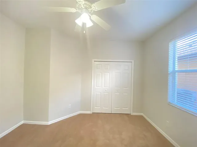 an empty room with windows and fan