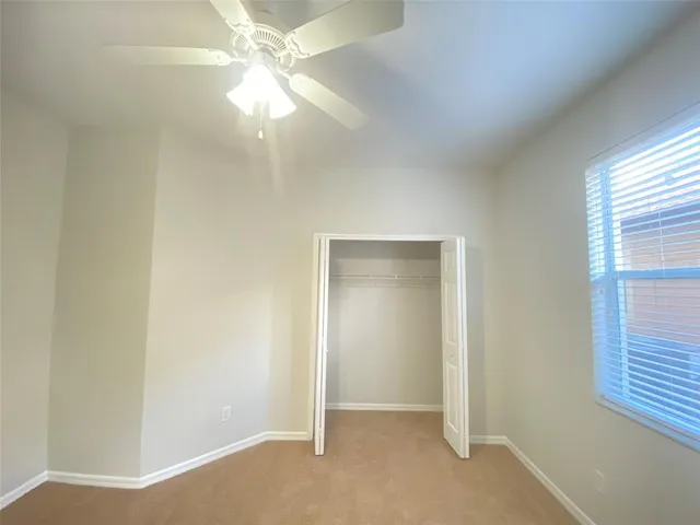 an empty room with a window and a fan