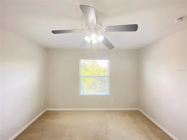 an empty room with a window and a fan