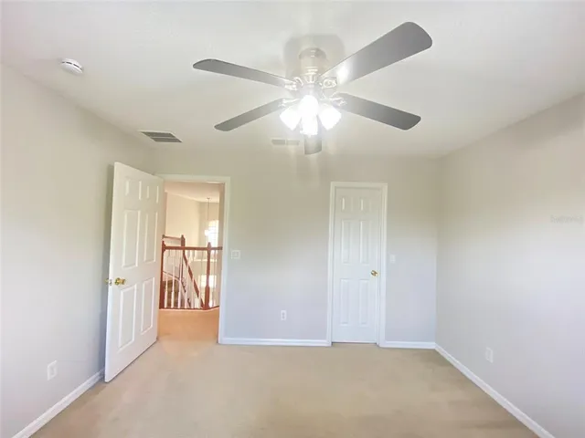 en empty room with fan and a ceiling fan