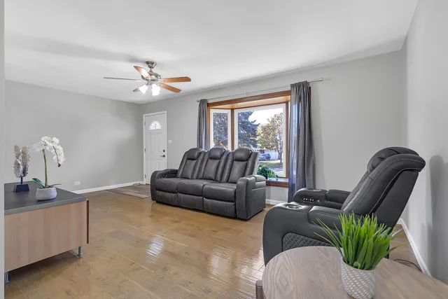 a living room with furniture a ceiling fan a lamp and a window
