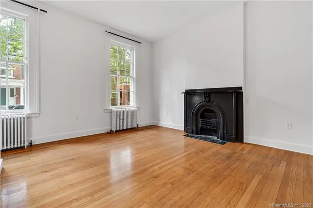 an empty room with windows and fireplace