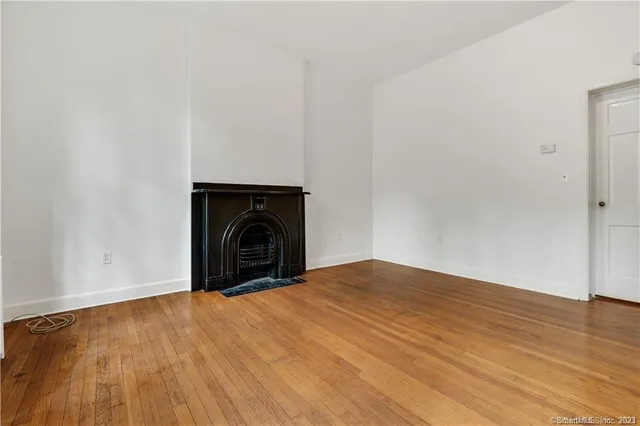 a view of empty room with wooden floor and fireplace
