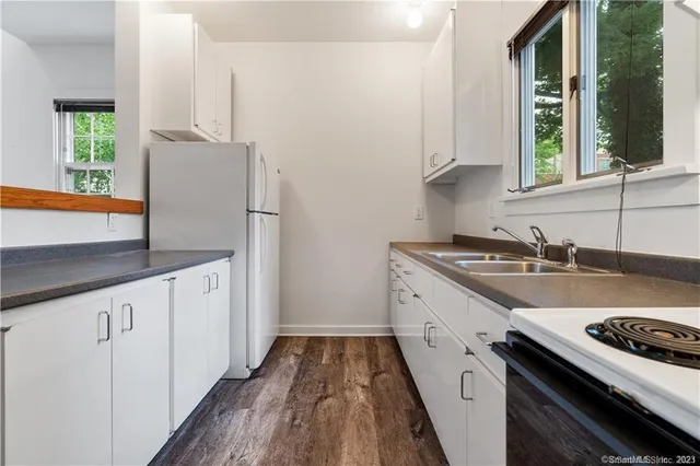 a kitchen with granite countertop a sink stove and refrigerator