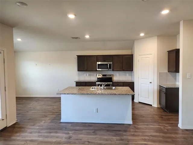 a large kitchen with stainless steel appliances granite countertop a stove a refrigerator and a microwave