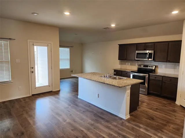 a kitchen with stainless steel appliances granite countertop a stove a sink and a refrigerator