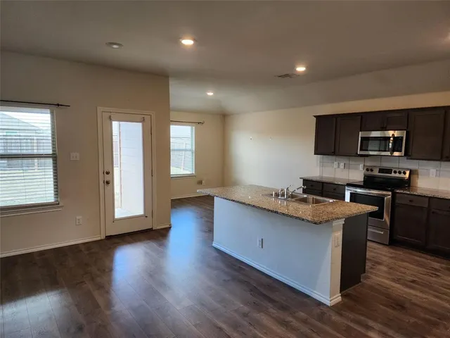 a kitchen with stainless steel appliances kitchen island granite countertop a stove a sink a refrigerator and a microwave