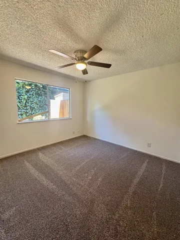 an empty room with windows and fan