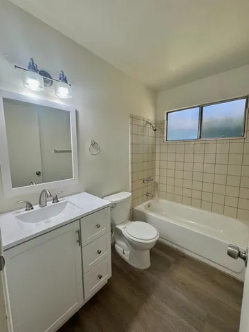a bathroom with a double vanity sink a toilet a mirror and bathtub