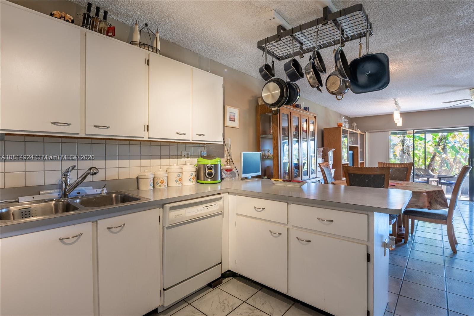 8814 Southwest 22nd Street, Unit B Boca Raton, FL 33433 - Photo 5 of 38 a kitchen with a sink dishwasher and white cabinets with wooden floor