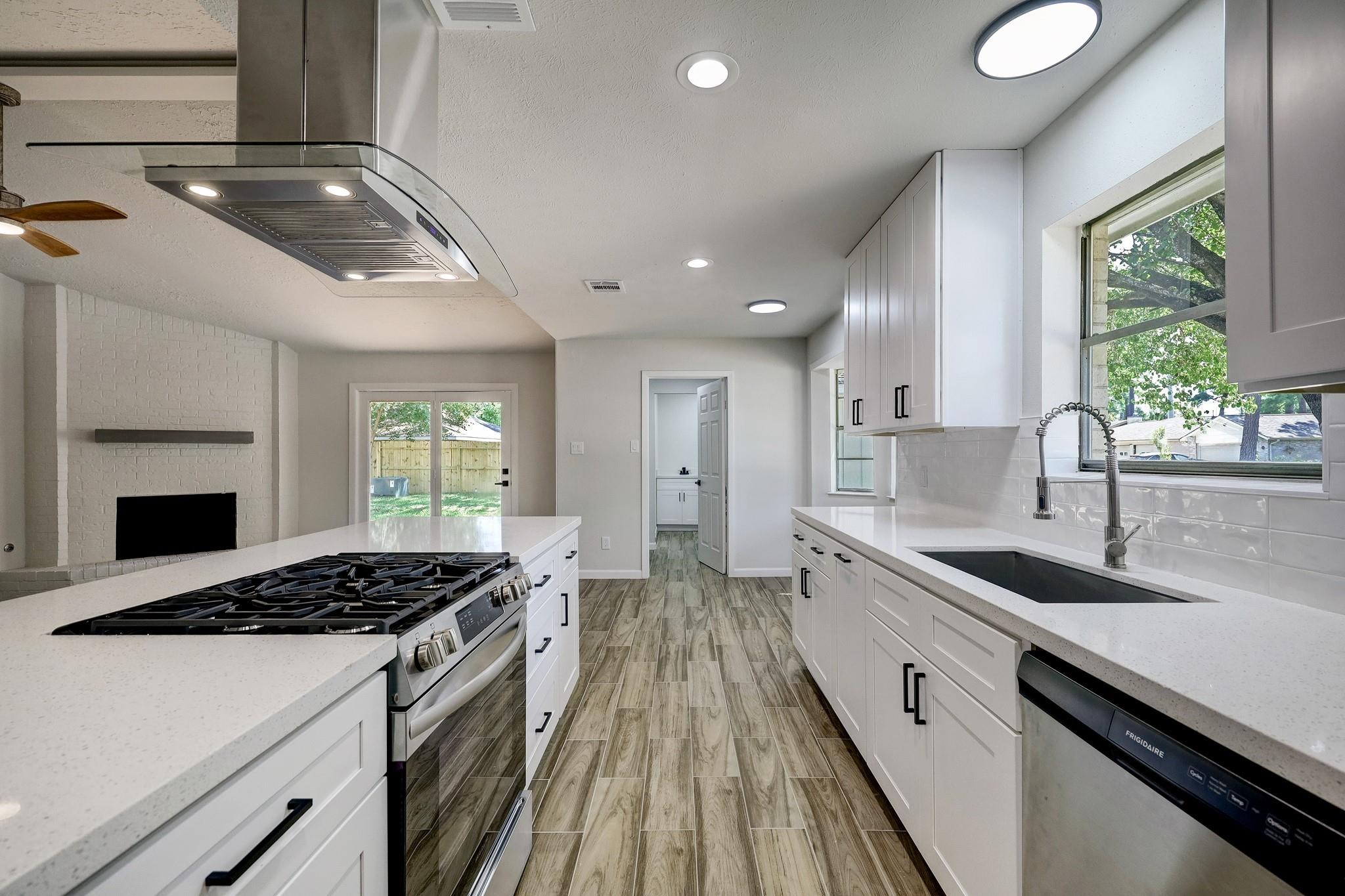 9723 Galston Lane Spring, TX 77379 - Photo 6 of 24 A standout culinary space, the kitchen features a clean, modern design with ample white cabinetry, quartz countertops, and a generously sized peninsula offering extra prep space and barstool seating. Lighting is thoughtfully layered with recessed and surface-mount fixtures.