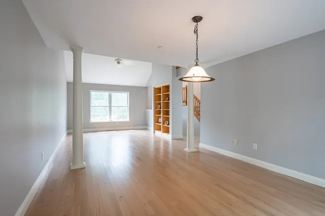 a view of a room with wooden floor ceiling fan and window