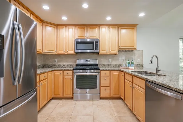 a kitchen with stainless steel appliances granite countertop a refrigerator stove a sink and a microwave