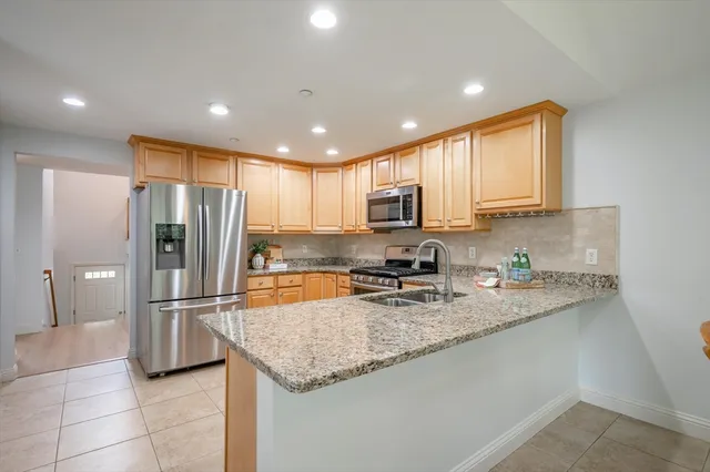 a kitchen with stainless steel appliances granite countertop a refrigerator a stove a sink and a refrigerator