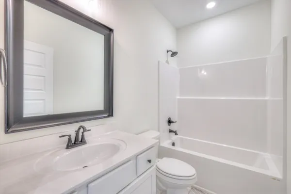 a bathroom with a bathtub shower sink vanity mirror and toilet