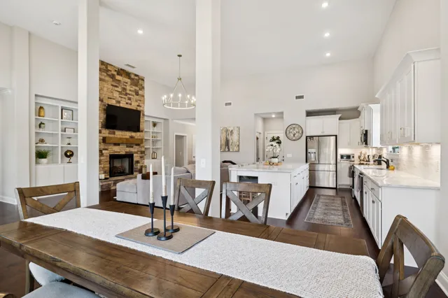 a room with stainless steel appliances kitchen island granite countertop a dining table chairs sink and cabinets