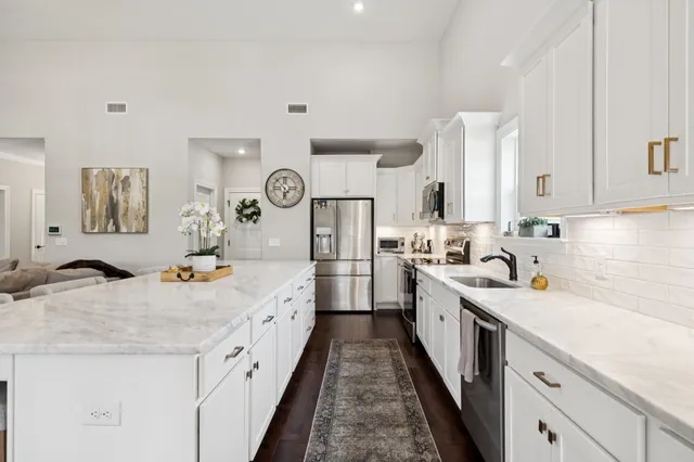 a large white kitchen with stainless steel appliances granite countertop lots of counter space and wooden floor