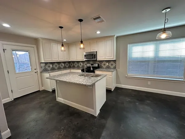 a kitchen with stainless steel appliances granite countertop a stove a sink and a microwave