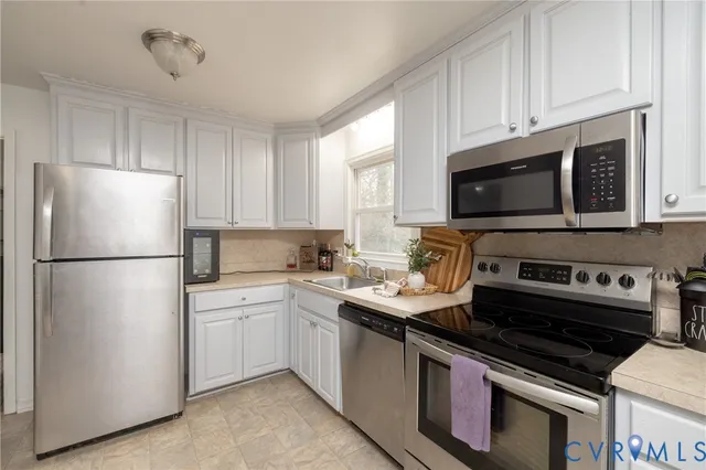 a kitchen with cabinets stainless steel appliances and a window