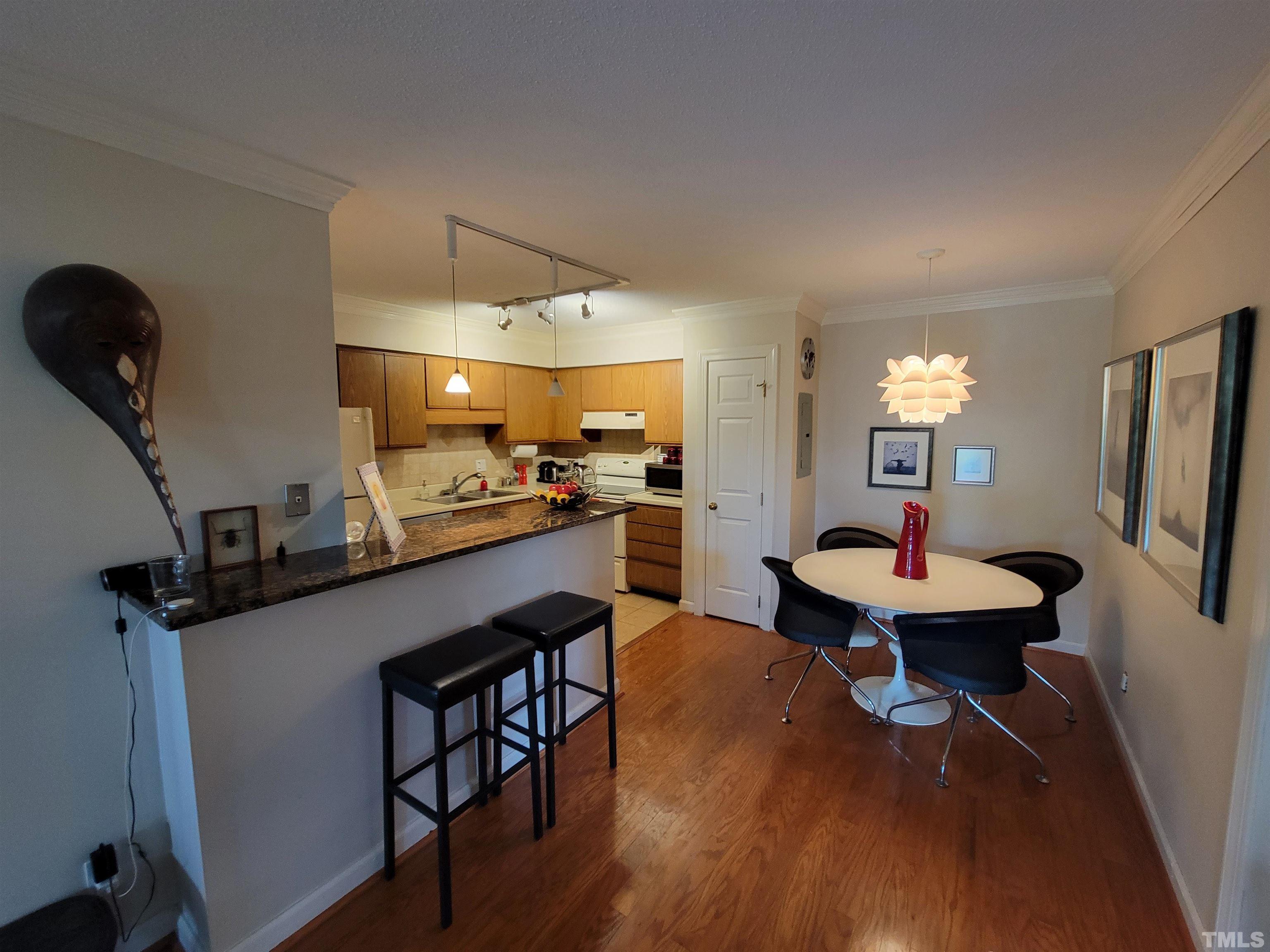 3601 Helix Court, Unit 302 Raleigh, NC 27606 - Photo 8 of 21 a kitchen with a table chairs refrigerator and microwave