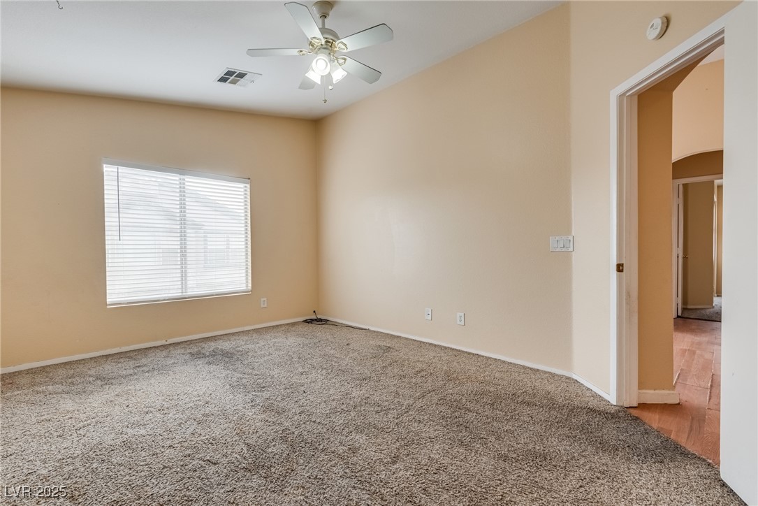 6354 Rusticated Stone Avenue, Unit 101 Henderson, NV 89011 - Photo 11 of 21 Carpeted empty room with arched walkways and a ceiling fan